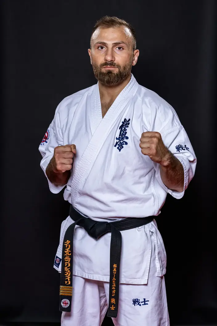 Sensei Tariel Nikoleishvili in a kyokushin gi and black belt, fists raised in fighting stance